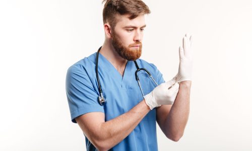 Portrait of a concentrated young doctor putting on sterile gloves hip orthopedic surgeon